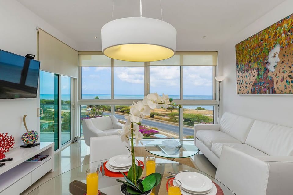 Relax in your bright, modern living space with sweeping ocean views through floor-to-ceiling windows. Fresh, elegant furnishings and vibrant art create a welcoming retreat for your coastal getaway.