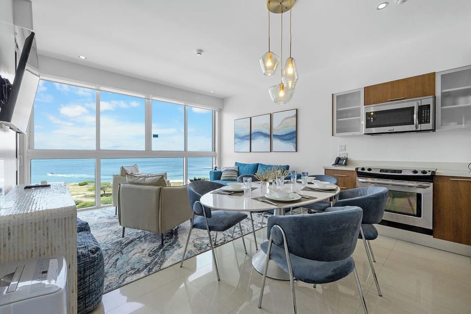 Open-concept living where sparkling ocean views greet you from your dining table. Modern kitchen with sleek appliances, cozy seating, and bright coastal charm make every moment effortlessly inviting.