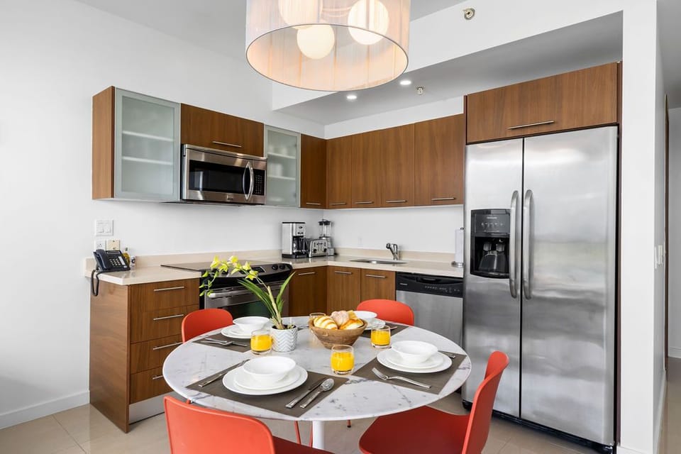 Your fully equipped kitchen invites you to cook together around the marble-topped table, with modern appliances and warm wood cabinets creating a welcoming space for family meals.