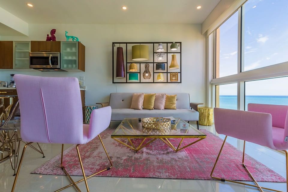 Watch the sparkling sea from your stylish living space, where modern furnishings, vibrant accents, and floor-to-ceiling windows create a coastal retreat you'll love.