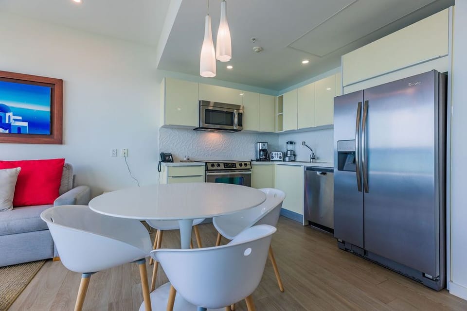 Bright, modern kitchen and dining area with stylish furnishings, stainless steel appliances, and thoughtful lighting create your perfect home base for coastal relaxation.