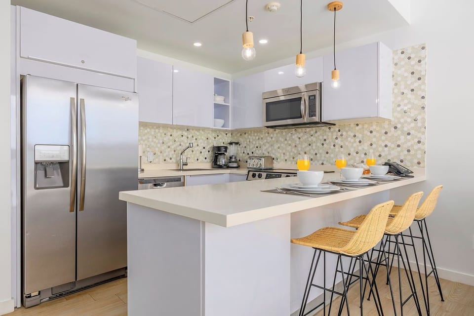 Step into your stylish kitchen featuring sleek white cabinets, modern pendant lighting, and a spacious island perfect for morning coffee or evening conversations.