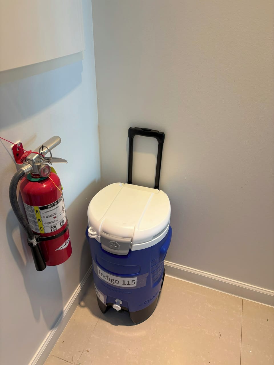 Practical amenities stored in a quiet corner include a fire extinguisher for your peace of mind and a wheeled cooler ready for beach trips or outdoor adventures.