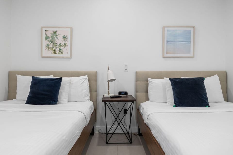Drift off in crisp white linens and matching twin beds with elegant navy accent pillows. Coastal artwork and a reading lamp create your tranquil escape.