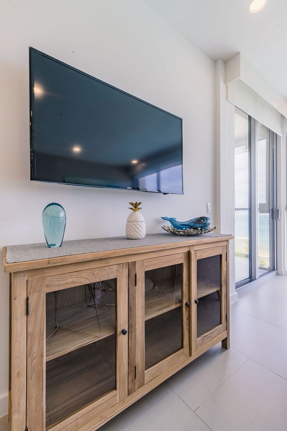 Unwind in this bright, airy living space with a wall-mounted TV and coastal-chic decor. Catch your favorite shows or simply enjoy the natural light streaming through the balcony doors.
