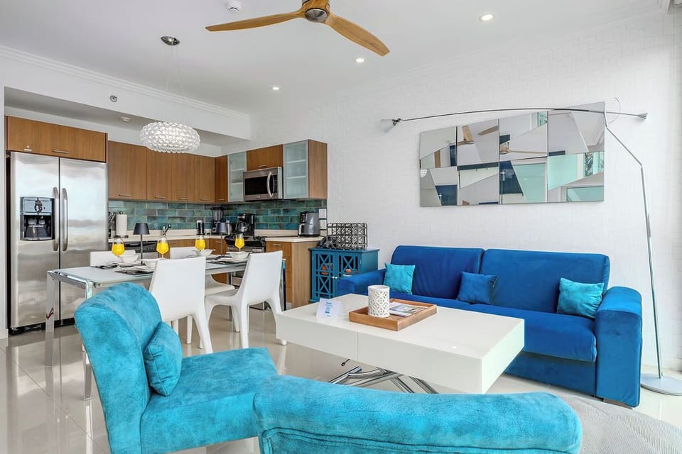 Relax into this bright, open living space where a vibrant blue sofa and cozy chaise invite you to unwind. Your fully equipped kitchen awaits, perfect for preparing anything from fresh juice to full meals.