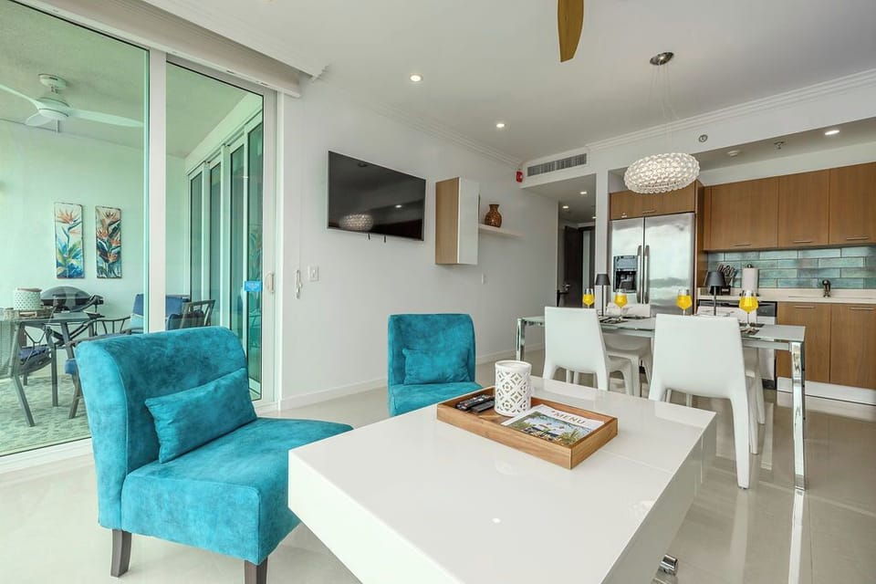 Sink into vibrant turquoise seating and savor your morning coffee in this bright, open-concept living space, where modern comforts meet coastal style. The fully-equipped kitchen awaits your culinary adventures.
