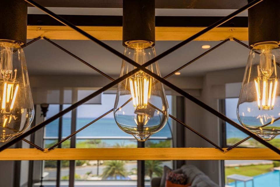 The warm glow of vintage-style pendant lights frames a stunning sea view, creating an inviting ambiance for your coastal getaway.
