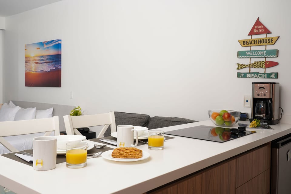 Start your mornings with fresh coffee and a simple breakfast setup in your cheerful, beach-themed space—complete with a cozy bed and fun coastal decor.