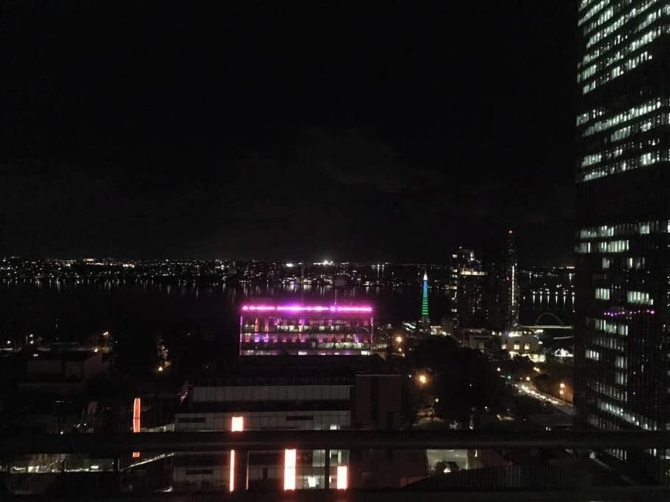 Lights twinkle, the view from the apartment. The City of Perth Council building is a colourful display as it continuously changes colours at night. The Bell Tower is also in the background.