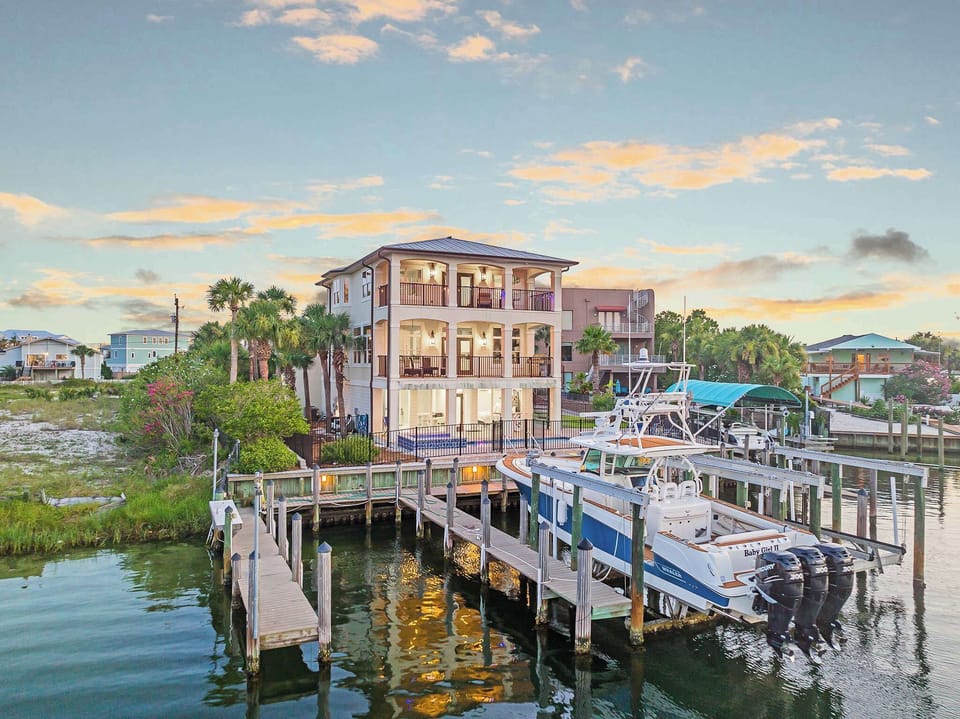 Waterfront perspective highlighting docks, boats, & the home’s prime position.