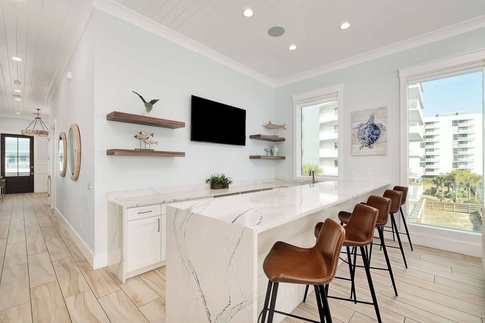 Gather around your stunning marble-topped breakfast bar, where leather stools meet modern elegance and wall-mounted TV entertainment awaits.
