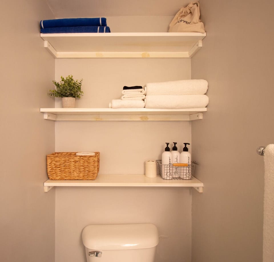 Spacious bathroom stocked with plush towels, beach towels, and essential toiletries including a hair dryer and shower products.