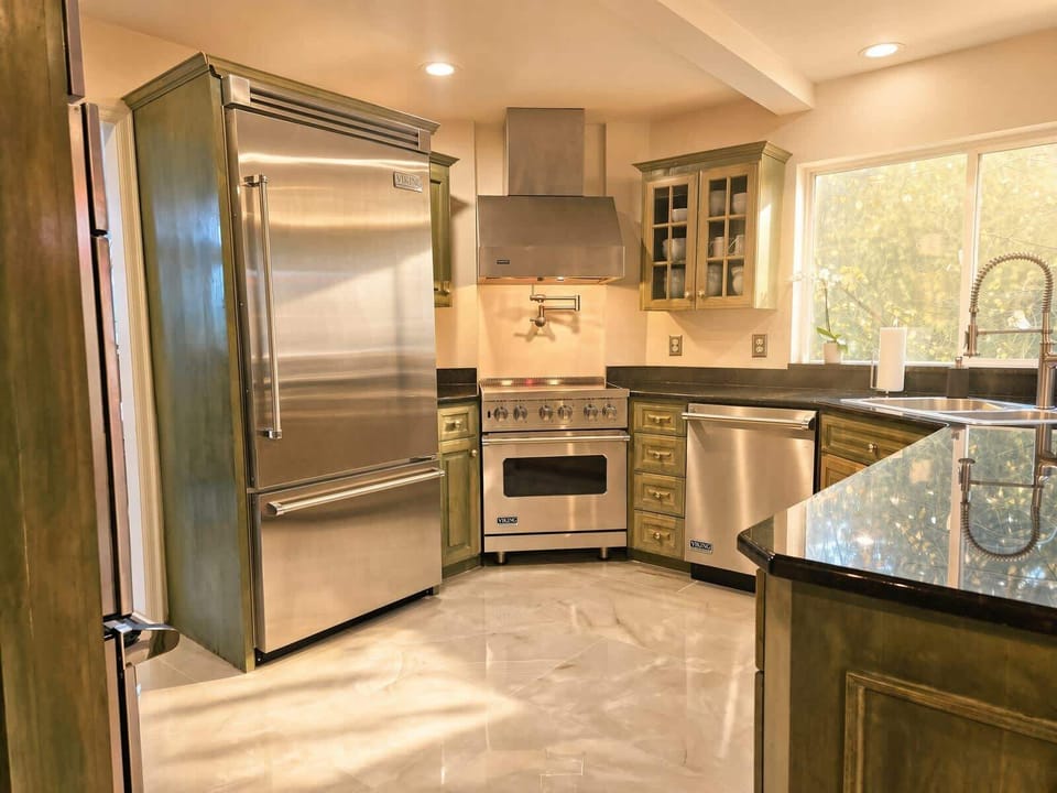 Large built in fridge and induction range with commercial infrared hood.