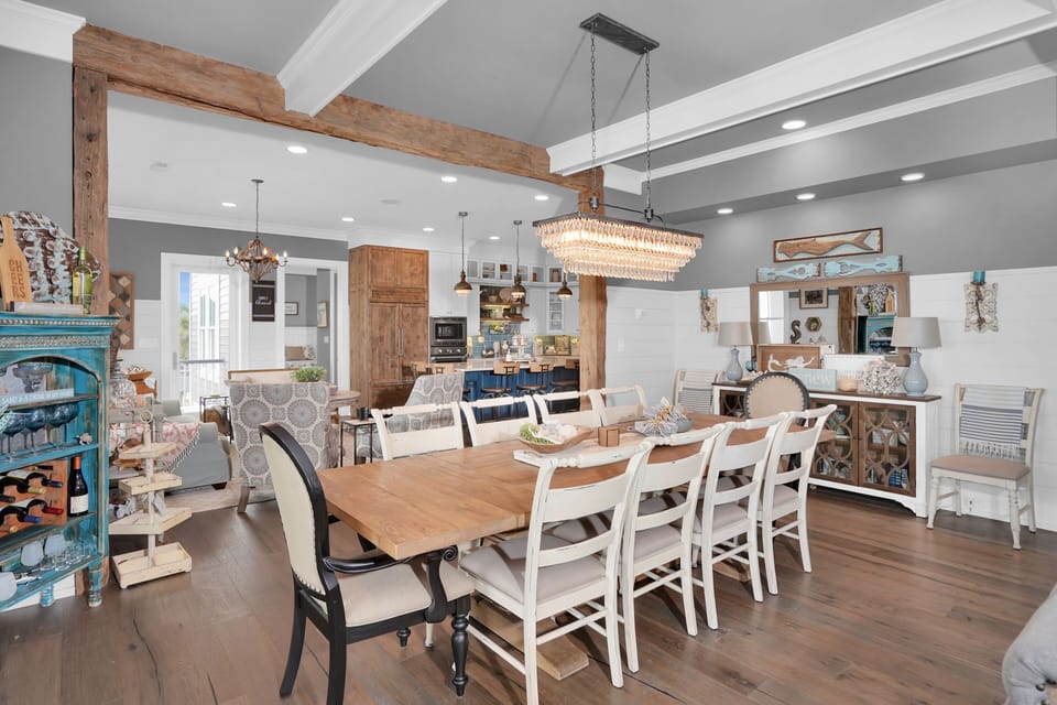 Gather around this stunning farmhouse dining table where rustic wood beams meet elegant crystal lighting, creating the perfect space for memorable meals.
