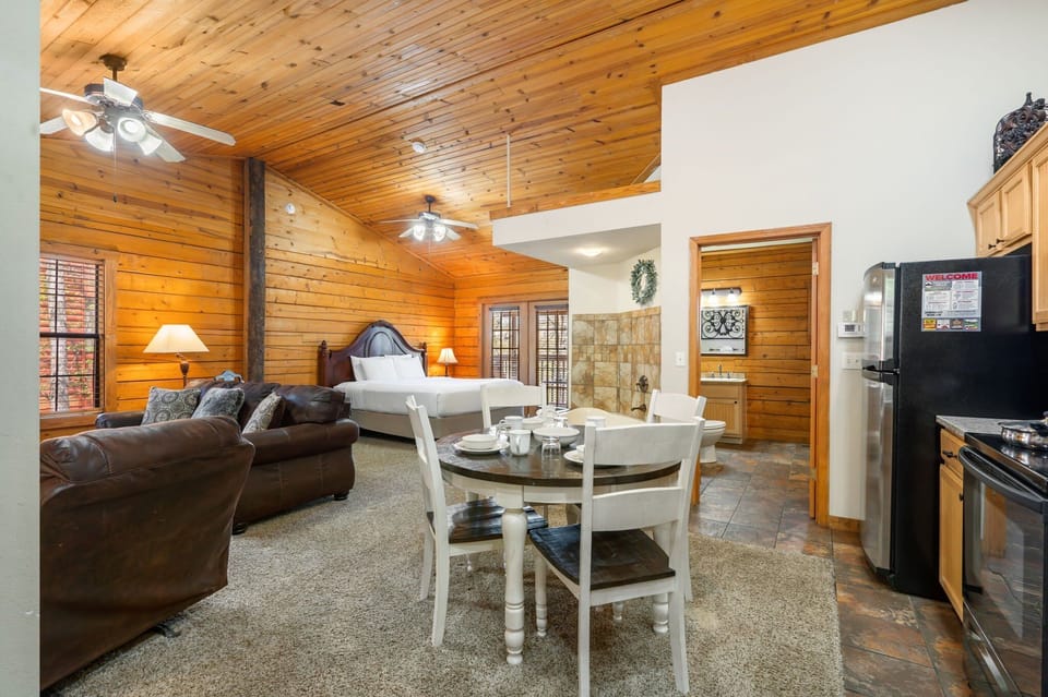 Experience the comfort of an open-concept retreat, where the cozy living area, fully equipped kitchen, dining space, and inviting king bed flow seamlessly together under warm wood-paneled ceilings. Perfect for couples or small families, this spacious layout offers both relaxation and functionality, all in one beautifully designed space.