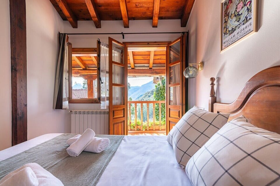 Cozy bedroom with wooden accents and a private balcony offering stunning mountain views.