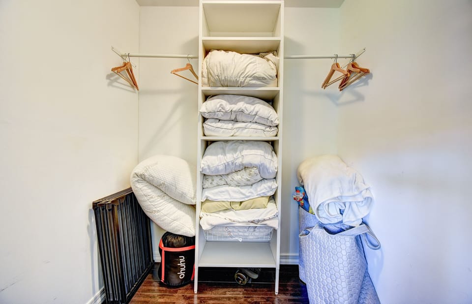 A view into our primary walk-in closet with spare pillows and air mattresses.