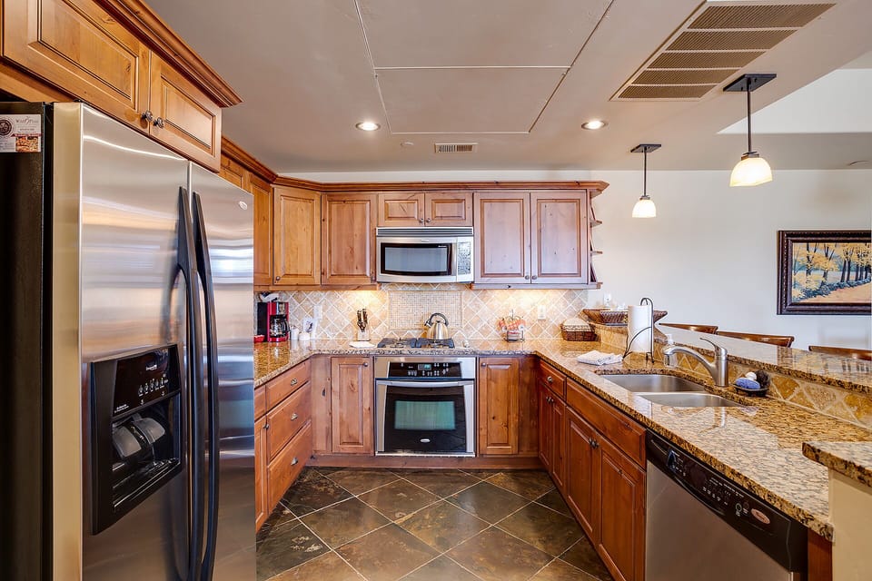 Your gourmet kitchen features rich wood cabinetry, granite countertops, and stainless steel appliances for effortless meal preparation during your stay.