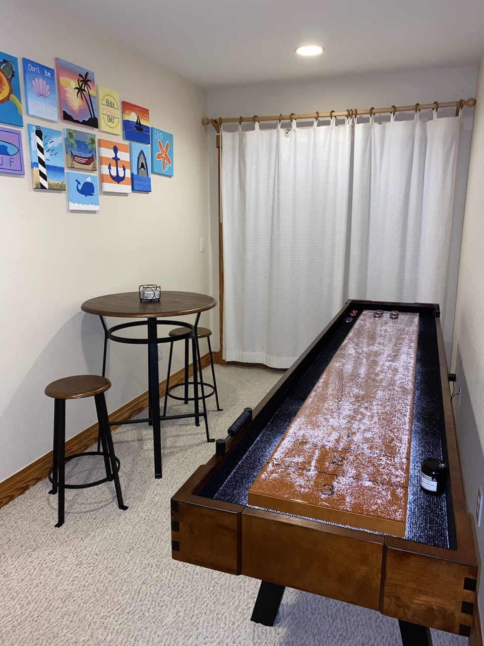 Lounge and shuffleboard area with artwork painted by family and friends