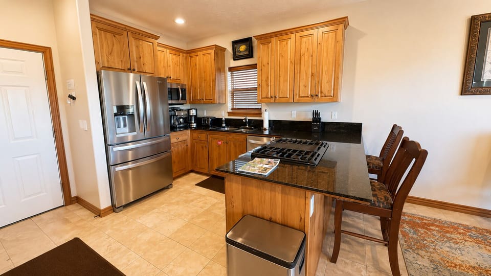 Prepare meals with ease in the fully equipped kitchen featuring granite countertops, stainless appliances, and bar seating.