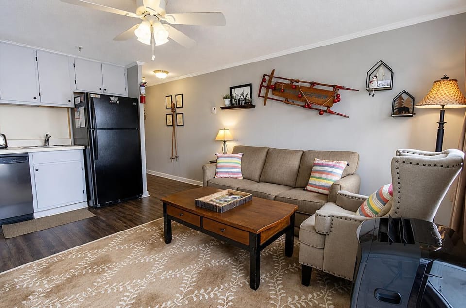 Living area with beige sofa, patterned armchair, wooden coffee table, and a wall-mounted vintage sled.