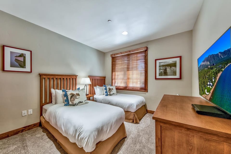 Unwind in this cozy twin bedroom where crisp linens and mountain artwork create your perfect retreat after adventure-filled days.