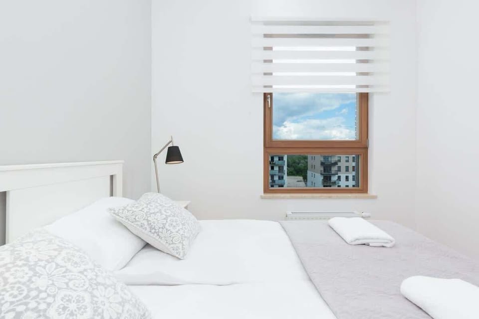 A bedroom featuring a white bed, mirrored wardrobe, and a serene atmosphere.