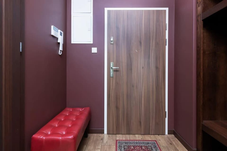 A clean and simple hallway with a red bench and wooden doors adding warmth to the space.