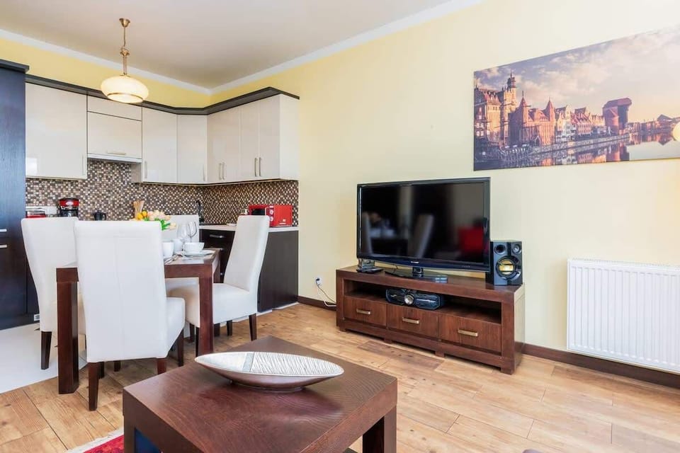 A living room featuring a dining table, a flat-screen TV, and a cozy seating area with a red and black color scheme.
