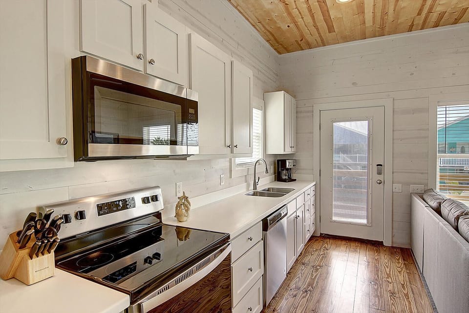 Cook your favorite meals in this bright, fully-equipped kitchen with modern appliances and charming wood ceiling details.
