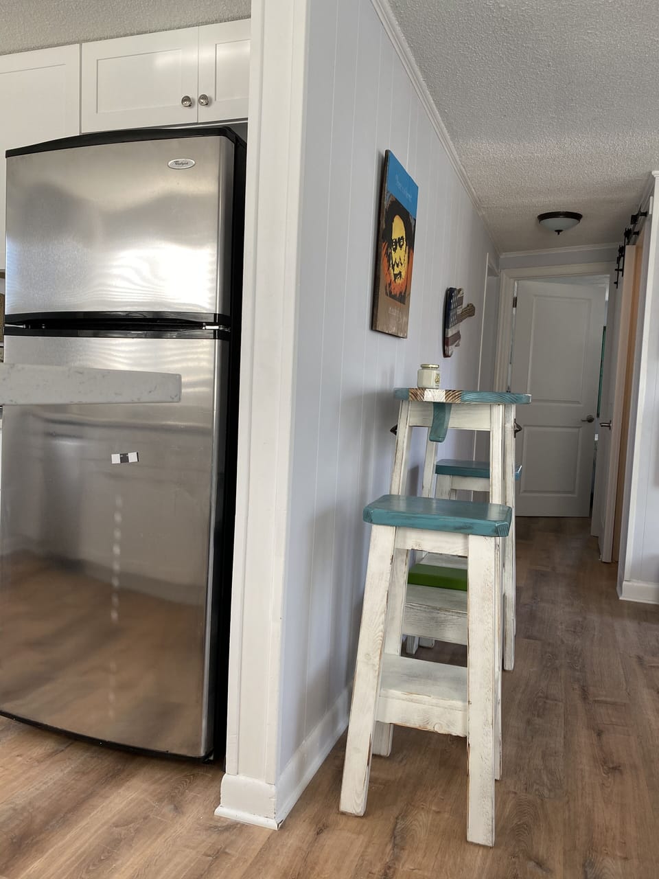 Nice sized refrigerator and a glimpse down the hall leading to a bathroom and 3 