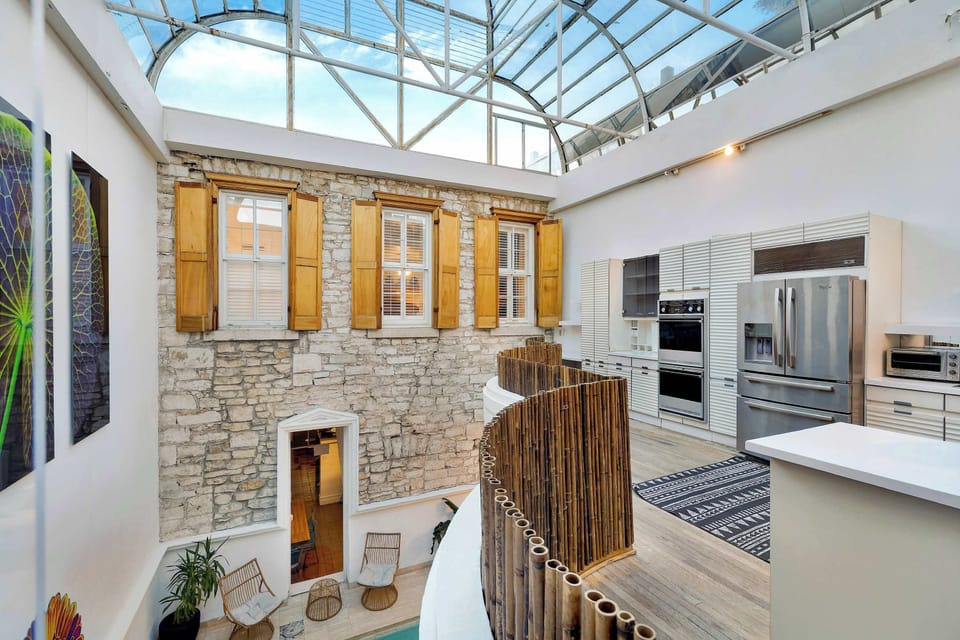 Stunning sunlit atrium kitchen blending modern design with historic limestone walls — the heart of the home.