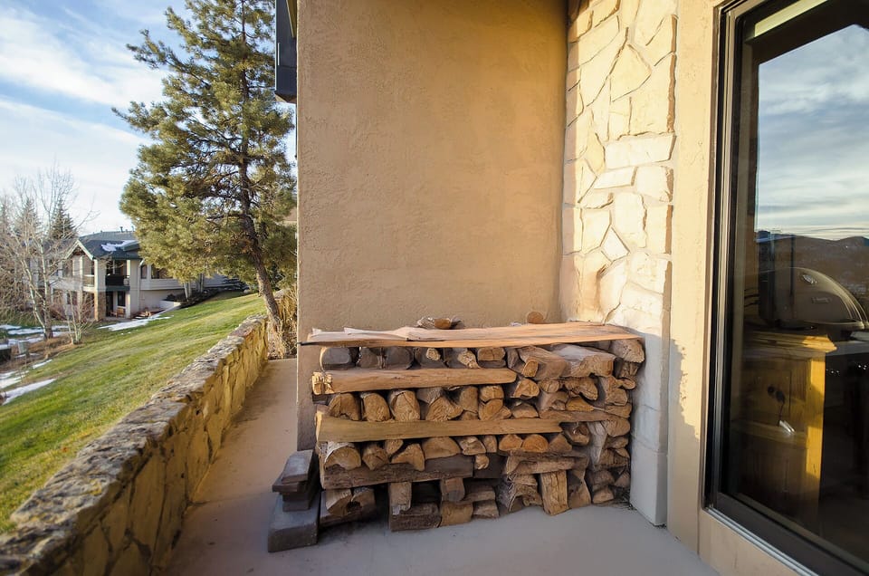 Step onto your private balcony where neatly stacked firewood awaits cozy evenings by the fireplace, with peaceful neighborhood views stretching beyond.