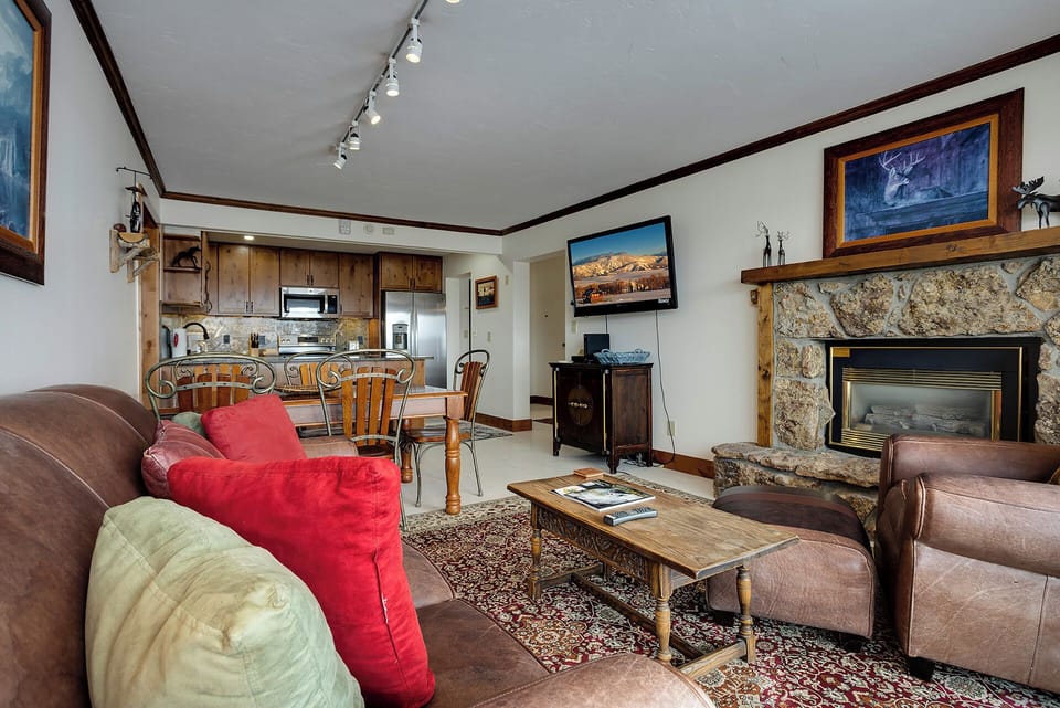 Cozy up in your inviting living space with plush leather seating, stone fireplace, and mountain views on TV while preparing meals in your fully equipped kitchen.