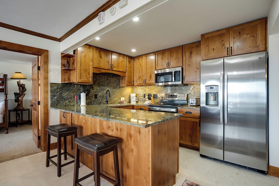 Your fully equipped kitchen awaits with warm wood cabinetry, granite counters, and stainless steel appliances—perfect for creating memorable meals together.