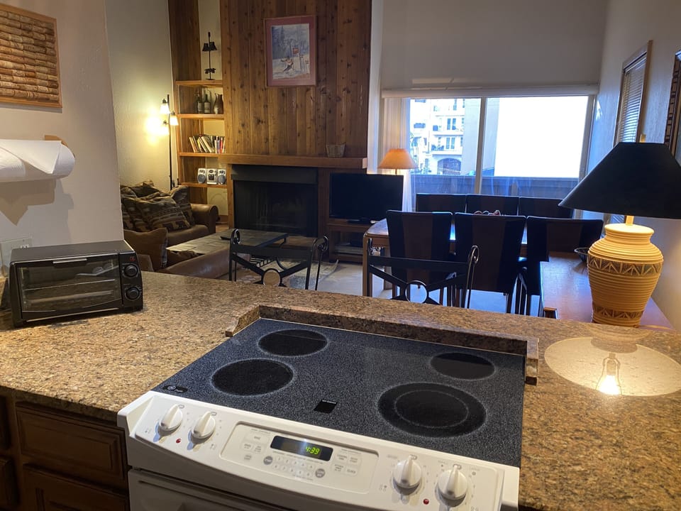 Kitchen w/ 2 bar seats leads to open living room/dining room w/ view of village