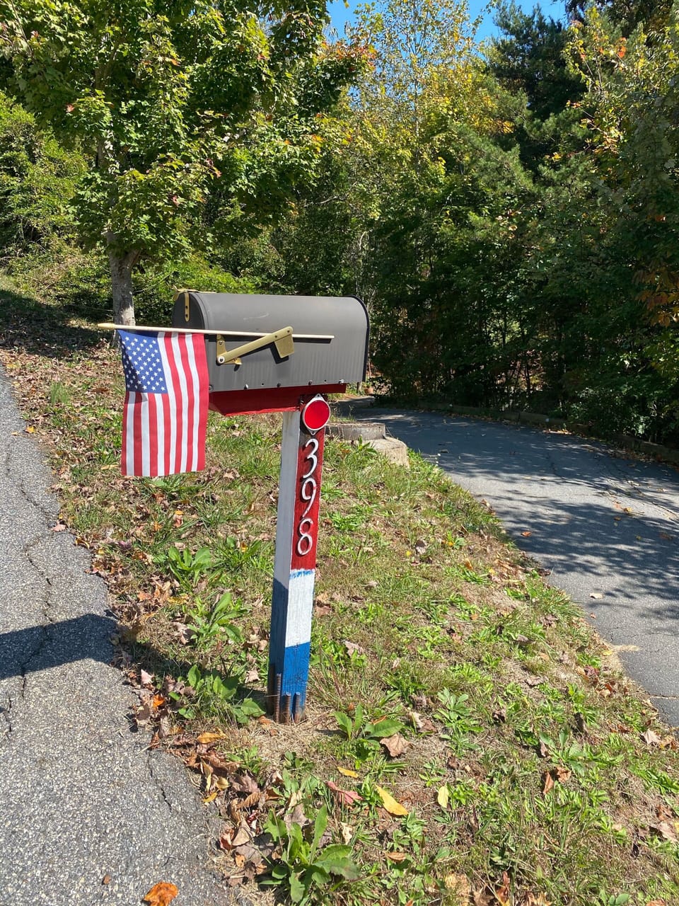 Red white and blue Mailbox post when you drive up the driveway on the right
