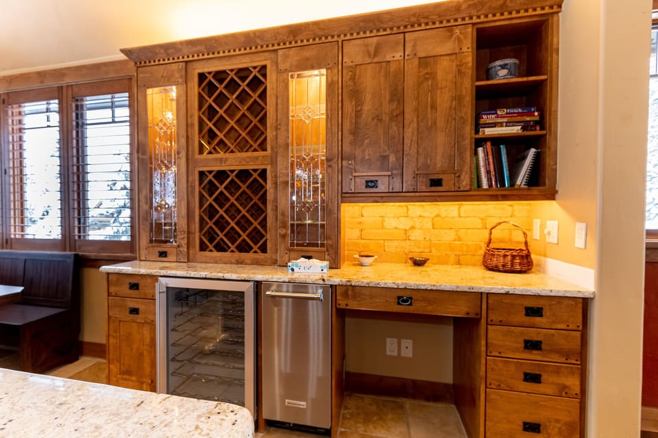 Your elegant kitchen workspace features warm wood cabinetry, granite countertops, and convenient built-in wine storage for memorable evenings.