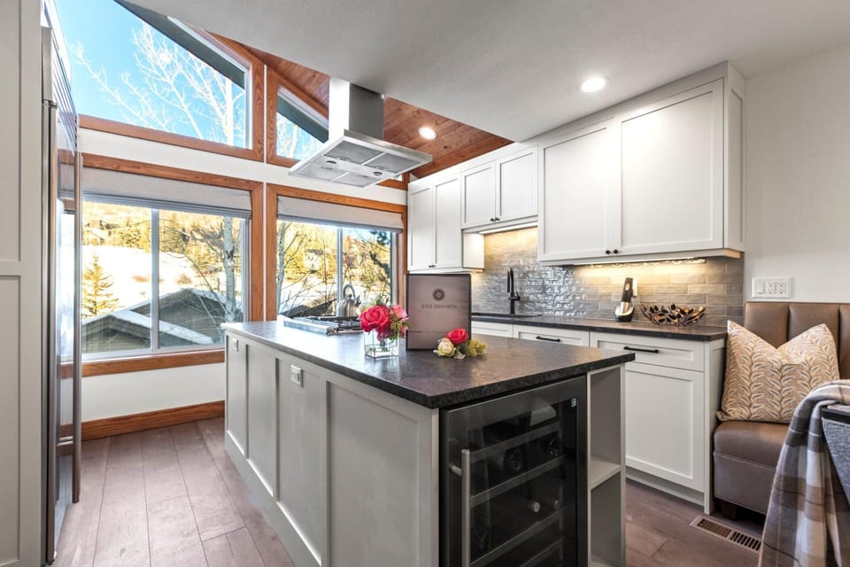 Airy kitchen with vaulted ceiling, scenic windows, and cozy breakfast bench.