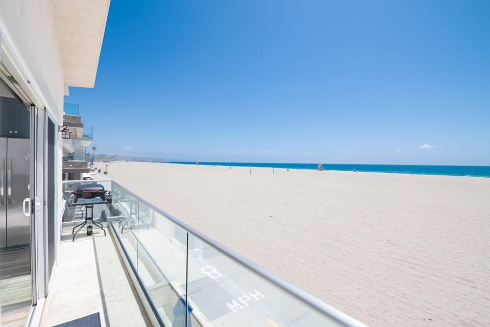 Sliding glass doors open to the balcony, which includes a small electric BBQ grill.
                