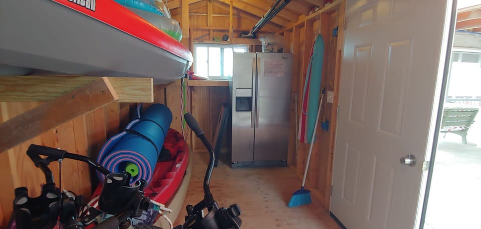 Full size refrigerator in shed for overflow groceries and fishing bait.