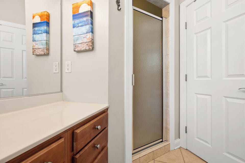 Bright en-suite bathroom with large vanity, glass shower, and coastal decor
