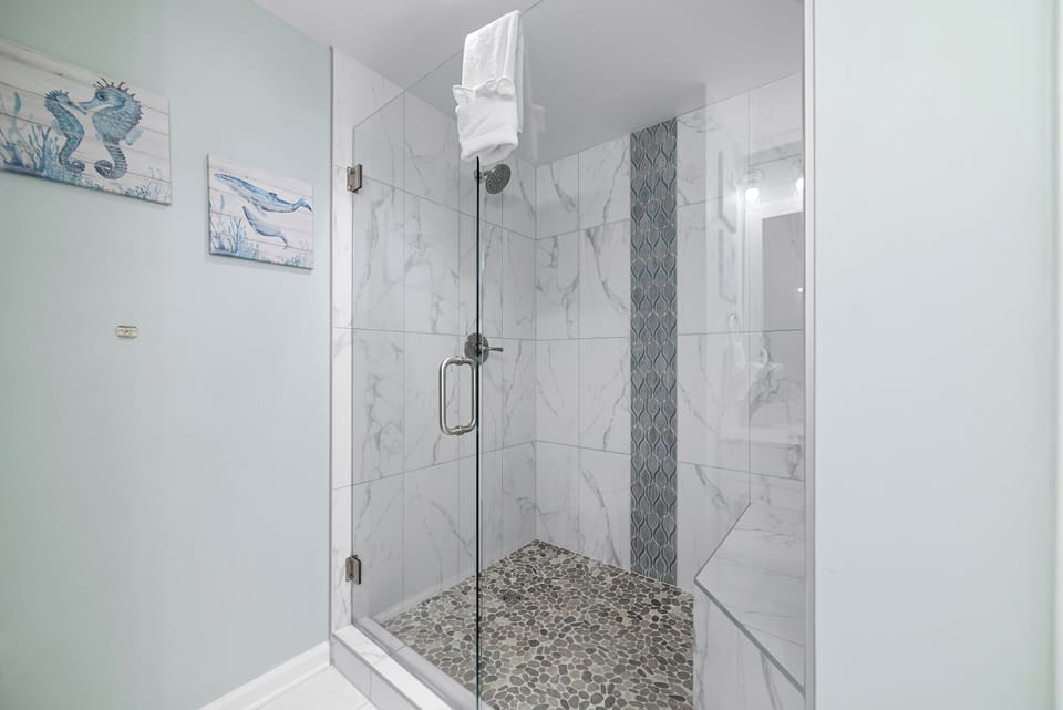 Featuring a sleek glass shower enclosur and a large mirror amplifying the space, this bathroom blends functionality with modern aesthetics.