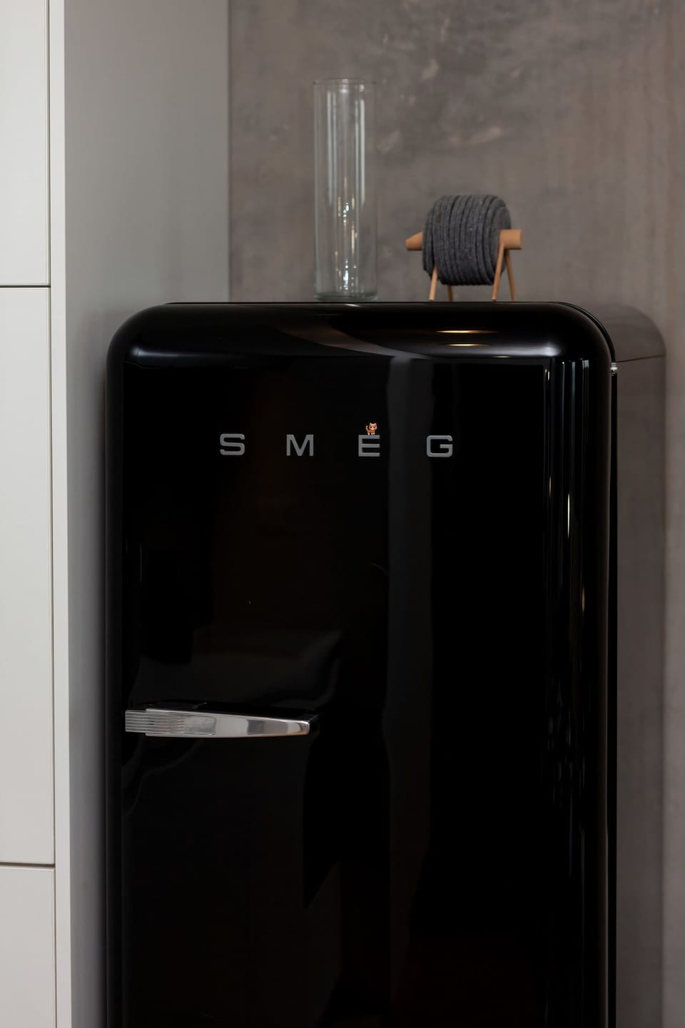 A stylish black mini-fridge placed against a minimalist wall, perfect for small spaces.
