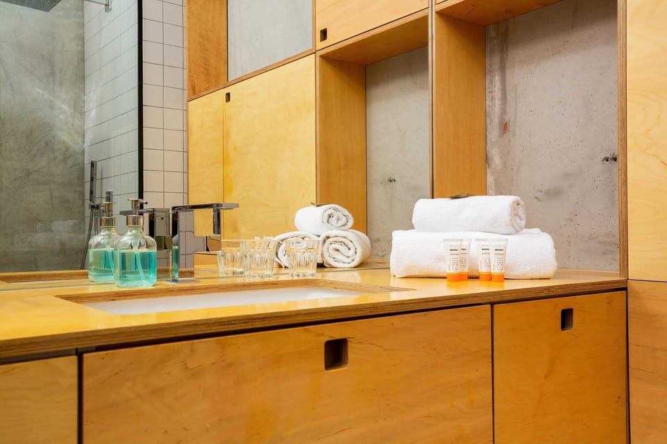 A wooden bathroom vanity with a large mirror, white sink, and neatly arranged towels and toiletries.