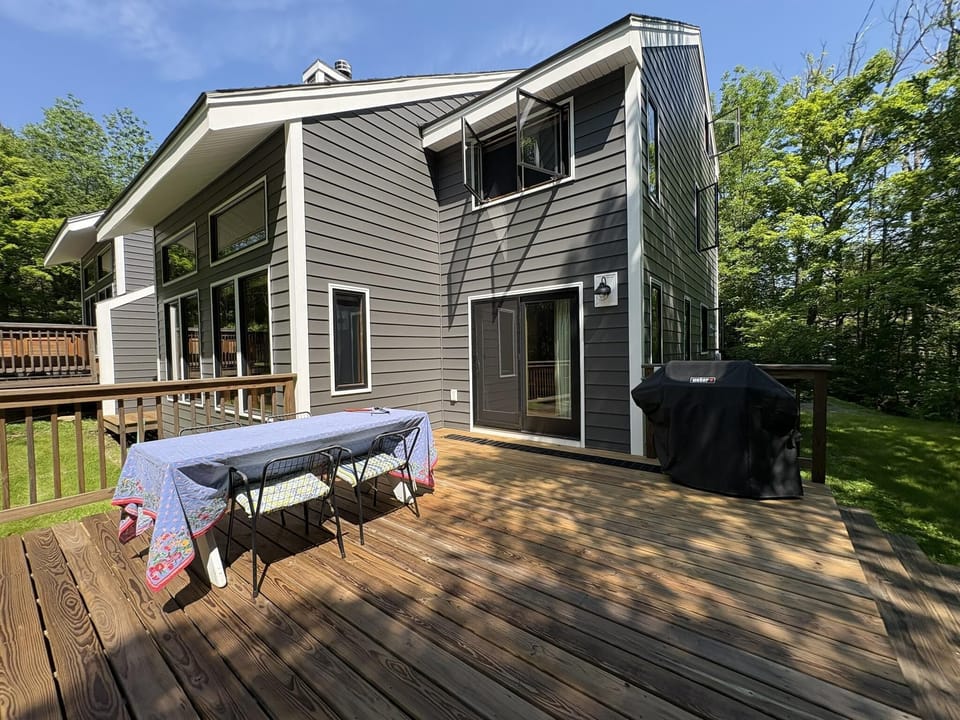 Spacious wooden deck with grill, outdoor dining and new siding exterior.
