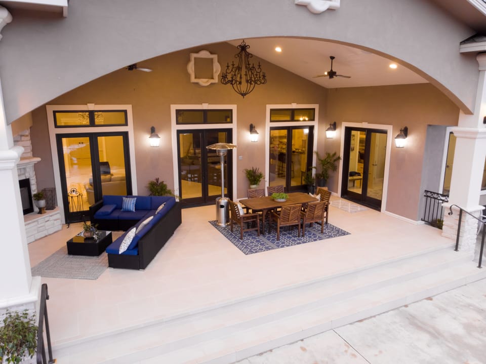 Outdoor back patio has an outdoor heater, fire place, dining, and seating.