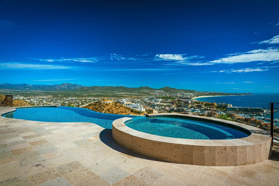 The circular hot tub set into the pool deck at Casa Cielo at Pedregal, beside the infinity pool with the ocean beyond.