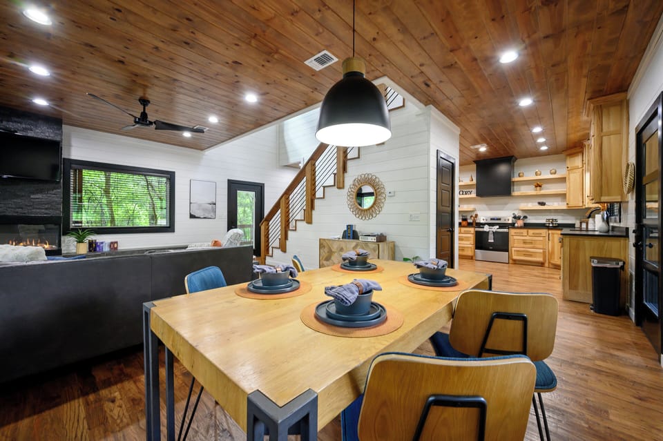 Gather around this beautifully crafted dining table beneath soaring wood-paneled ceilings, where warm natural light and modern farmhouse style create your perfect home-away-from-home setting.